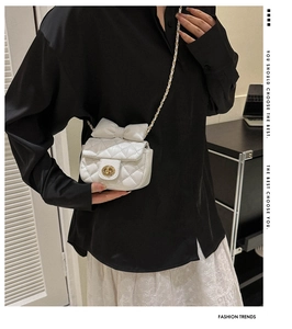 Close-up of a white quilted crossbody bag with bow detail worn by a model in lifestyle setting