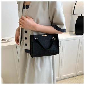 Detail of black crocodile texture bag with gold metal clasp and sleek chain strap