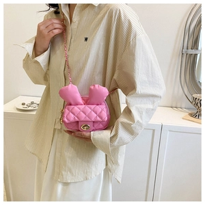 Detail of pink quilted rabbit ear mini crossbody bag with gold chain strap on model
