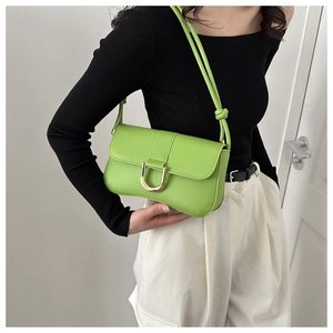 Detail of bright green shoulder bag featuring a gold horseshoe buckle and knotted strap