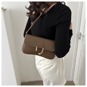 Detail of dark brown leather underarm bag featuring a metallic U-shaped gold buckle