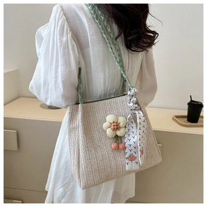 Detail of woven straw tote featuring floral accents and a decorative printed silk ribbon