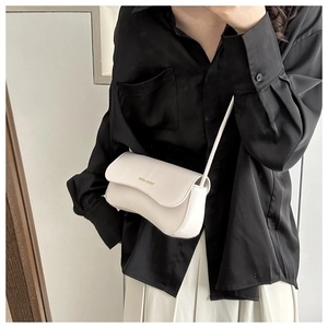 Close-up of cream crossbody bag featuring gold lettering and premium leather texture