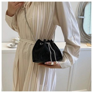 Detail of black rhinestone bucket bag featuring silver chain and pearl drawstring charms