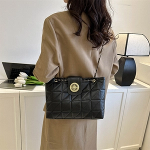 Borsa tote nera trapuntata con catena e fibbia dorata indossata a spalla da una modella