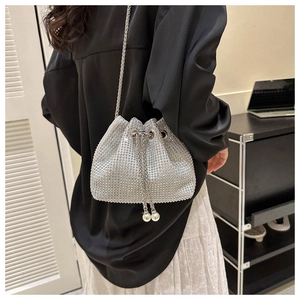 Detail of silver rhinestone bucket bag featuring chain drawstring and pearl accents