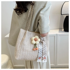 Close-up of beige woven tote bag with 3D cotton flower charm and decorative ribbon