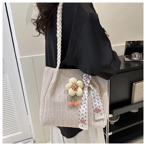 Close-up of beige woven tote bag featuring a floral charm and patterned silk ribbon strap