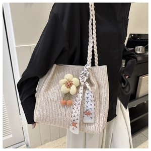Detail of straw woven tote bag with floral charm and printed silk scarf handle