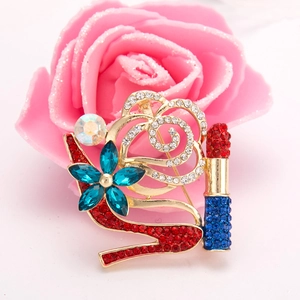 Nahaufnahme der goldenen Brosche mit Strass-Stöckelschuhen, Lippenstift und Blumendetails