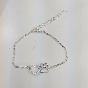 Detail of silver alloy bracelet featuring hollow heart and dog paw prints with lobster clasp