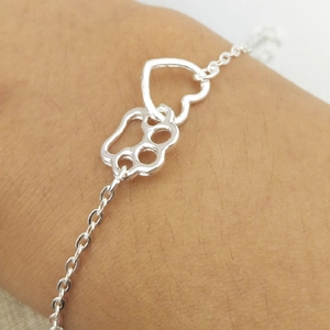 Silver alloy heart and paw print charm bracelet with O-chain on female wrist
