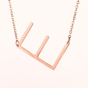 Primer plano del collar con colgante de letra E en oro rosa y cadena minimalista de acero inoxidable