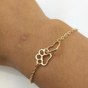 Eco-friendly gold alloy bracelet featuring hollow heart and paw print charms on wrist