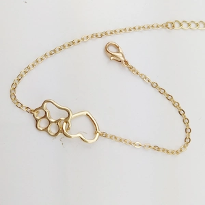 Detailed macro view of the interlocking golden heart and hollow paw pendant on a fine chain