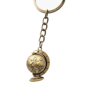 Vintage bronze spinning globe keychain with world map relief on a white background