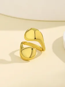 Macro detail of gold-tone liquid metal style adjustable alloy nail ring on white stand