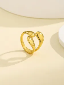 Detail shot of golden liquid metal nail ring with mirror finish on white geometric stand
