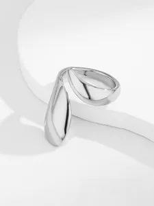 Close-up of a silver streamlined open ring with a modern teardrop design on a white pedestal