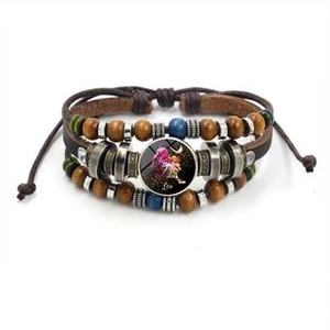 Detail van vintage gevlochten leren armband met houten kralen en Leeuw sterrenbeeld hanger