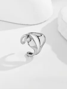 Macro shot of silver fluid-style open ring with polished wavy lines on abstract blocks