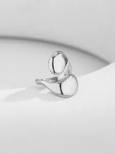Macro view of polished silver irregular open ring with glossy metallic droplet ends