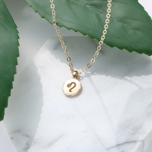 Detailopname van gouden Leeuw sterrenbeeld ketting op wit marmer met groene bladeren