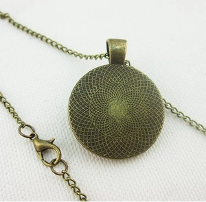 Dettaglio del retro di un ciondolo in bronzo vintage con incisione geometrica a spirale