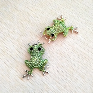 Green crystal frog brooches with sparkling rhinestones on natural wood background