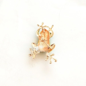 Detail view of the golden frog brooch back with secure pin and textured finish