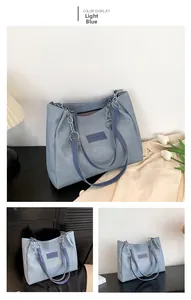 Close-up of light blue denim texture tote bag with silver chain strap and brand label