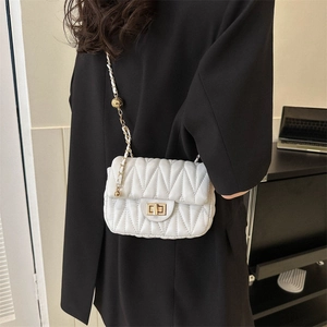 Sac à bandoulière matelassé blanc avec chaîne dorée et perle de réglage sur blazer noir