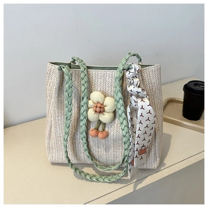 Detail of straw woven tote bag featuring floral pendant and decorative silk scarf