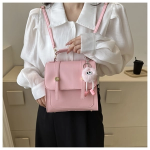 Détail d'un sac à main carré en cuir PU rose avec boucles dorées et breloque en peluche