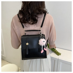 Vue de dos d'un mannequin portant un sac à dos polyvalent en cuir PU noir et pompon rose