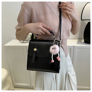 Détail du sac à main en cuir PU noir mat avec un charmant pendentif monstre rose en peluche