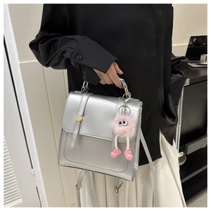 Détail du sac bandoulière argenté avec boucle en métal et breloque peluche monstre rose