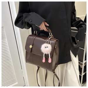 Détail du sac en similicuir marron foncé avec boucle dorée et breloque peluche rose