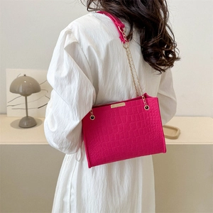 Magenta crocodile pattern tote bag with gold chain strap shown from a 45-degree angle