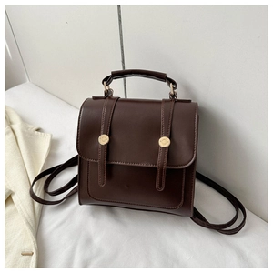 Détail du sac à dos en similicuir marron foncé avec boucles dorées et poignée