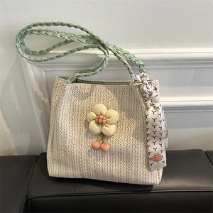 Straw tote bag with green braided handles, floral charm and patterned silk ribbon