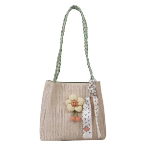 Straw tote bag with green handles, floral charm and patterned silk scarf detail