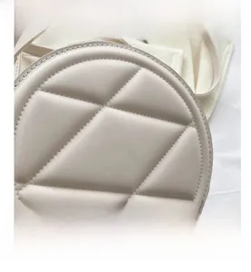 Detailed macro view of cream-white round handbag with geometric quilted faux leather texture