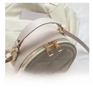 Detail view of smooth double gold zippers on cream quilted round crossbody bag