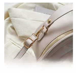 Close-up of white round quilted PU leather handbag with elegant gold metal hardware hooks