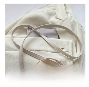 Detail of adjustable strap and gold buckle on a cream quilted round crossbody bag