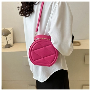 Detail of a rose red round quilted crossbody bag with golden metal buckle and strap