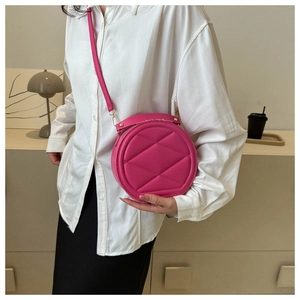 Close-up of fuchsia quilted round crossbody bag with gold hardware and top handle