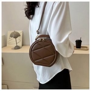 Detail of deep brown quilted round crossbody bag with gold hardware and dual zipper
