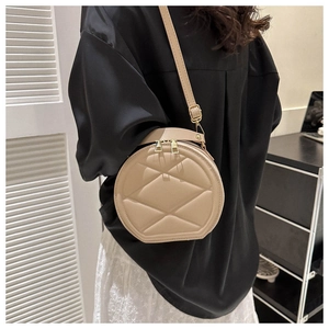 Detail of beige round crossbody bag with geometric quilted pattern and gold zipper